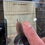 トヨタ ハイエースのフロントガラスに発生した飛び石のヒビ割れを指で確認する様子