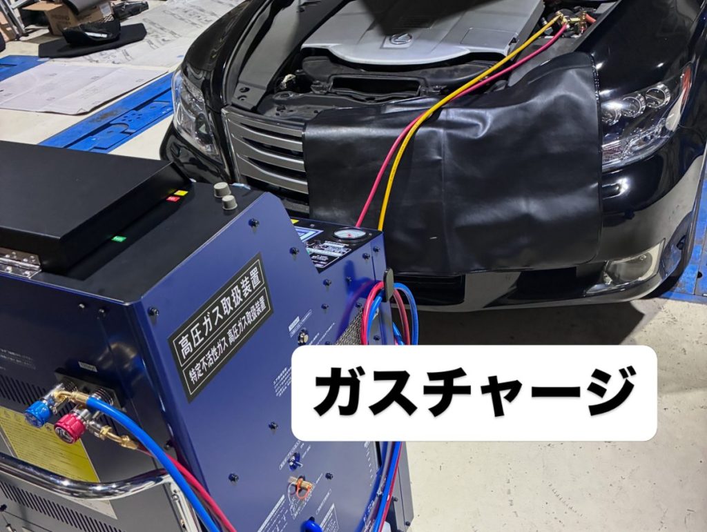 リアエアコン脱着に伴い専用機材でエアコンガスチャージを行っている作業風景
